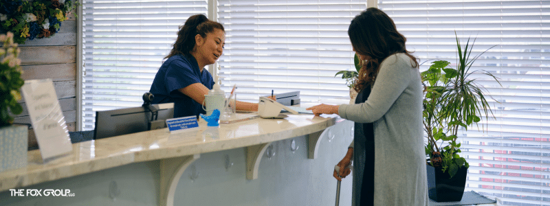 Front desk receptionist showing medical office HIPAA compliance best practices while checking in a patient.