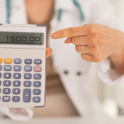 Physician pointing to medical practice expenses on a calculator.